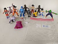 Full view of 11 assorted Dragon Ball Z action figures with some loose accessories on white background.