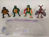Four Teenage Mutant Ninja Turtles and mutant action figures displayed together with a Ziploc bag.
