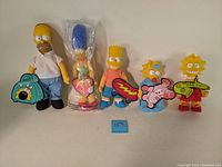 Full group of five Simpsons dolls including Homer, Marge (sealed), Bart, Maggie, and Lisa, all with original hang tags visible.