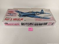 Top view of box showing Guillow's branding and image of blue Grumman F6F-3 Hellcat scale model. Features text details like wingspan and model scale.