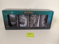 Front box view showing four Harry Potter-themed 16oz glasses through window packaging in teal box
