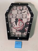 Full front view of the coffin-shaped wall clock highlighting the character and skull motif on the clock face.