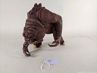 Front angle of the brown Rancor figurine showing textured skin, claws, and limbs.