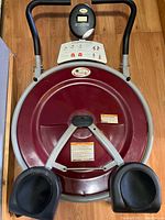 Front view of Ab Circle Pro showing circular maroon rotating base with removable knee pads and digital display.