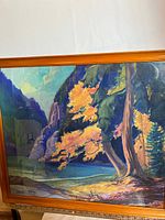 Full view of framed watercolour painting showing landscape with tree, water, mountains in vibrant colors.