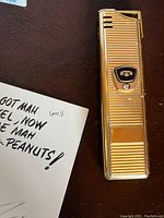 Close-up of the gold-tone BC Tel lighter with diamond accent and horizontal ridges.