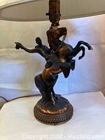 Front view of the vintage lamp showing the cowboy figurine on a rearing horse, base with rope detail, and lampshade.