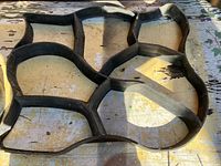 Close-up of one of the black plastic concrete molds showing the interconnected, irregular stone pattern shape.