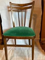 Front view of vintage wooden chair showing emerald green corduroy upholstered seat and original wood finish