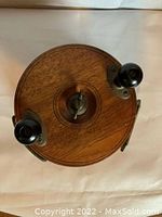 Top view of vintage wooden Peetz fishing reel showing dual black handles and wood finish.