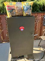 Front view of closed smoker with three wood chip bags on top