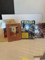 Photo of four books standing upright showing covers. Two on fishing and two on furniture.