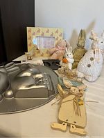 Photo showing metal rabbit cake pan, Easter egg cookie pan, yellow rabbit picture frame, three stuffed bunnies, white wooden bunny, small metal duck, and pale green bunny dish