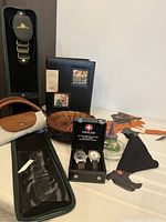Photo showing the tie holder, photo album, two watches in Wenger case, shopping bag, Halloween decoration, and frog witch candle on plate.