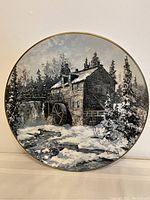 Full view of the circular collector plate depicting a winter sawmill scene with snow and trees, signed Keirstead