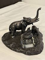 Front and side view showing detailed metal elephants, textured base and square glass ink well with hinged lid featuring leaf decoration.