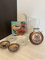 View of all items including the painting, glass pitcher, canteen, cut glass candle holders, and African dishes on a light surface.