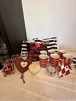 Full view of Valentine-themed items arranged on table including mugs, bags, candles, and decorations.