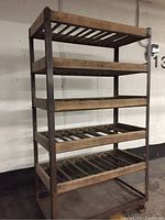 Front angle view of the 5-shelf wooden rack on casters showing slatted wooden shelves and metal frame.