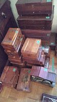 Top view showing multiple wooden rectangular boxes stacked, some with metal clasps, various sizes and wood finishes visible.