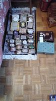 Overview of assorted trinket boxes, jewelry boxes and photo frames displayed on rug and shelf