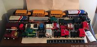 Front view showing multiple Buddy L toy vehicles including school buses, trucks, and trailers arranged on a flat surface with a ruler for scale.