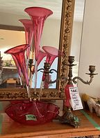 Front view of brass candelabra and pink glass epergne with five trumpet vases and bowl