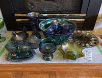 Full lot of carnival glassware including punch bowl, glasses, egg dish, vase, and other serving pieces on fireplace mantle