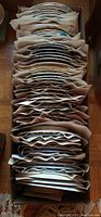 Photo of a large box holding at least 45 individually wrapped china plates, stacked vertically with packing paper between them.
