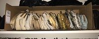 Wide shot of assorted sequined, beaded, and fabric clutches in a cardboard box, showing variety of colors and metallic finishes