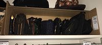 Cardboard box containing approximately 15 dark-coloured clutches lined in two rows