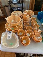 Full view of Fire King glassware including plates, cups, saucers and large serving pieces on a table.