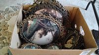 Cardboard box filled with stacked ornate oval metal frames