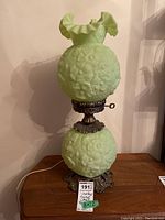 Front view of lamp showing top ruffled shade, middle globe, lower globe and base