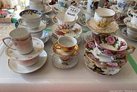 Overview of assorted porcelain teacup and saucer pairs arranged on a table