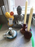 Overall image of candle holders, Buddha statue, glass vase with fruit