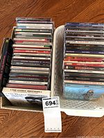 Two containers on floor holding numerous CDs, visible titles include rock and classical genres