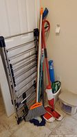 Photo of drying rack, spray mop, broom, blue mop, and cleaning packages leaning against a white wall