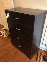 Front view of four drawer dresser with dark wood finish and metal curved handles on each drawer.