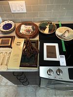 Lot arranged on kitchen counter including plates, frames, and plate stands.