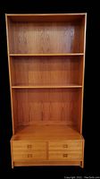 Front view of light wood veneer shelving unit with three open shelves and four drawers