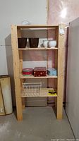 Full view of the pine shelf showing pots and tins, wire basket, and a small box on shelves.