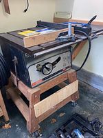 Full side view of the bench saw on a custom wooden wheeled stand showing size, build, and condition.