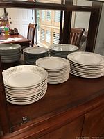 Multiple stacks of Carlton China dinnerware including plates, bowls, and serving pieces showing their quantity and design.