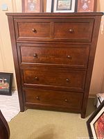 Front view of wooden chest showing four drawers with metal knobs and wood grain finish.