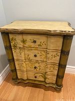 Front view of the chest revealing four drawers with floral painted design and metal pulls