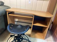 Child's wooden desk with curved edge and open storage, paired with black tractor-style chair