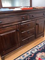 Photo of dresser front showing drawers and side doors with dark wood finish and round black knobs