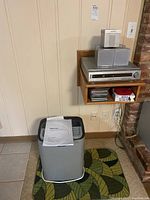 Hisense dehumidifier placed on floor with instruction manual on top, silver color with black vents.