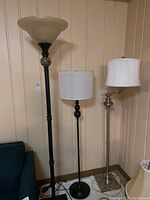 Three floor lamps standing next to each other showing relative height and design differences.